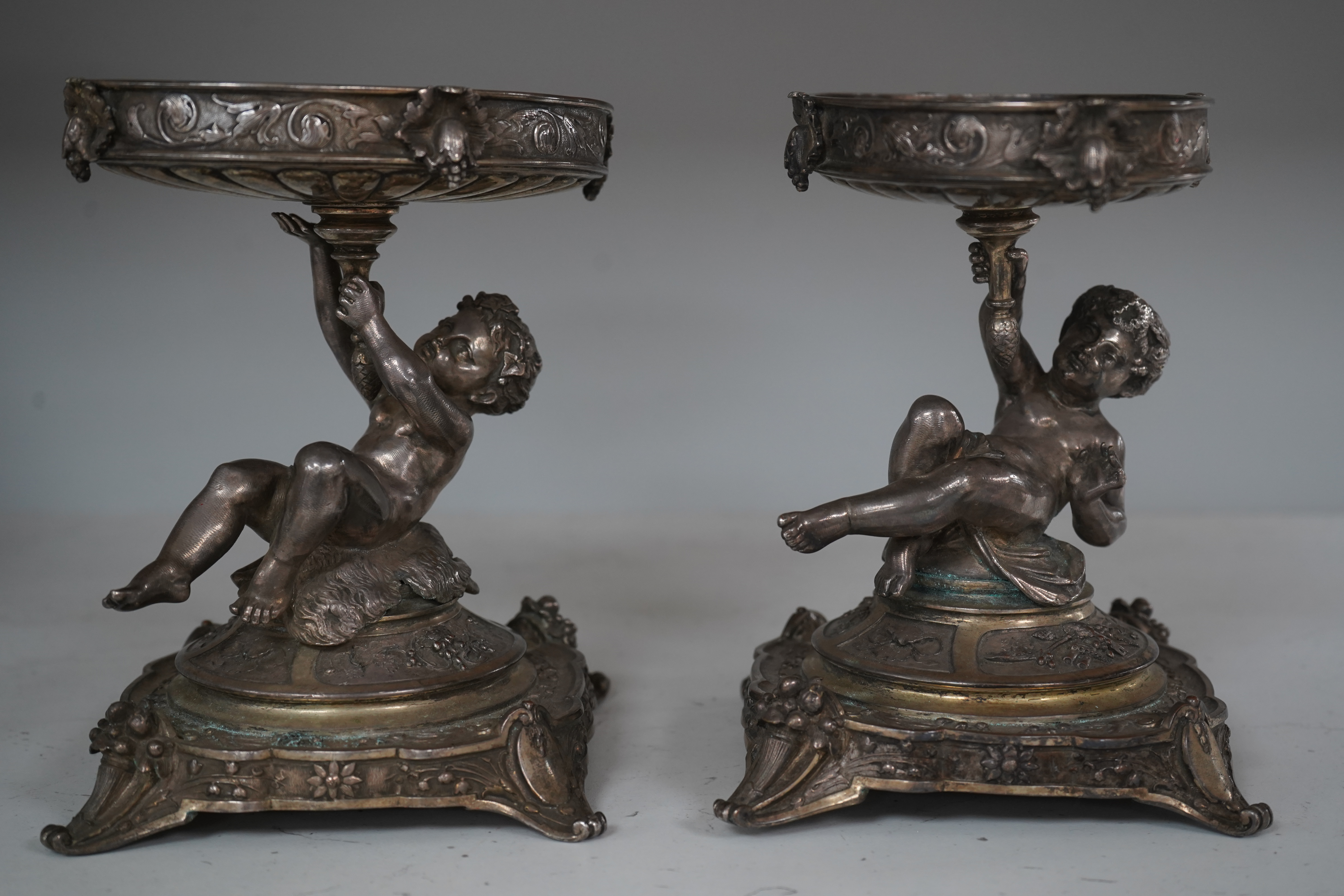 A pair of early 20th century Elkington & Co. silver plated ‘putti’ stands, 17cm. Condition - fair to good